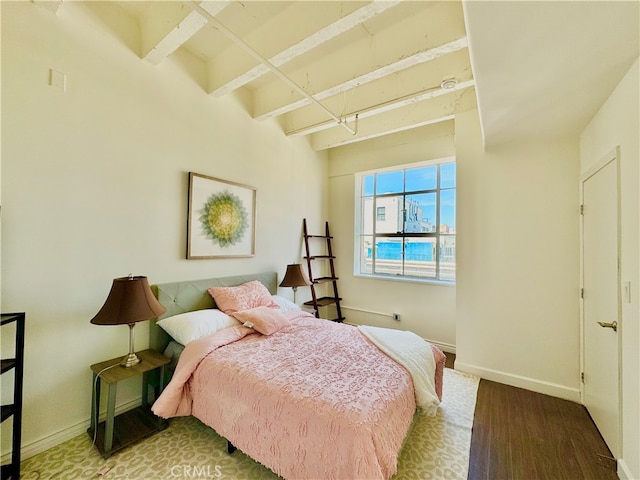 bedroom featuring beamed ceiling and hardwood / wood-style flooring