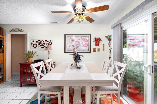 tiled dining space with a textured ceiling and ceiling fan