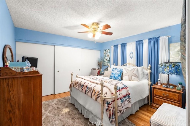 bedroom featuring ceiling fan, light hardwood / wood-style floors, a textured ceiling, and a closet