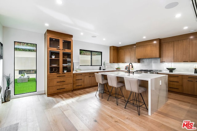 kitchen featuring a kitchen breakfast bar, a kitchen island with sink, and light wood-type flooring