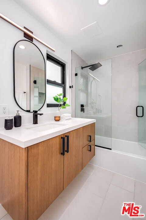 bathroom with tile patterned floors, vanity, and shower / bath combination with glass door