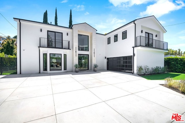 rear view of house with a balcony and a garage