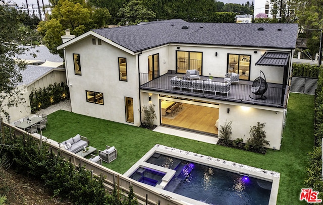 rear view of property featuring an outdoor living space, a yard, a balcony, and a swimming pool with hot tub