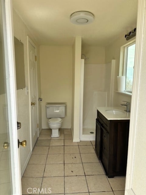 bathroom with vanity, a shower, toilet, and tile patterned floors