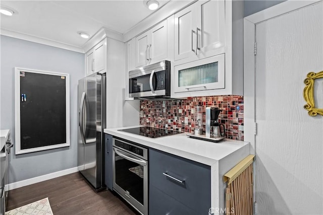 kitchen with white cabinets, dark wood-type flooring, stainless steel appliances, backsplash, and crown molding