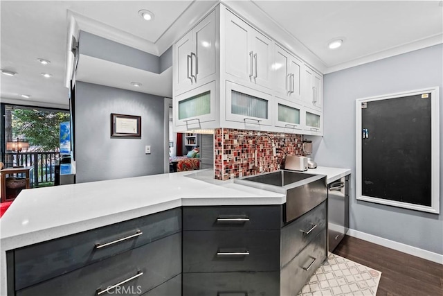 kitchen featuring stainless steel dishwasher, kitchen peninsula, white cabinetry, ornamental molding, and dark hardwood / wood-style flooring