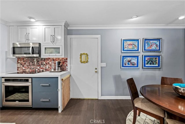 kitchen featuring white cabinets, dark hardwood / wood-style flooring, stainless steel appliances, decorative backsplash, and crown molding