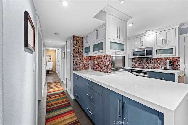 kitchen with white cabinets, appliances with stainless steel finishes, tasteful backsplash, sink, and blue cabinets