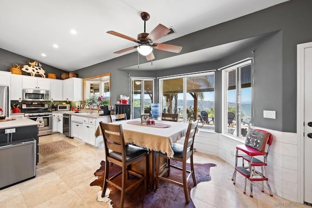 dining room featuring ceiling fan, sink, light tile patterned floors, and vaulted ceiling