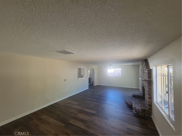 unfurnished living room featuring a textured ceiling, a fireplace, and dark hardwood / wood-style flooring