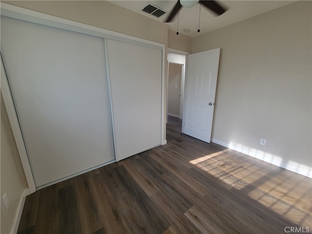 unfurnished bedroom with ceiling fan, dark wood-type flooring, and a closet