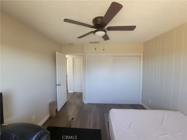 bedroom with ceiling fan, a textured ceiling, a closet, and dark hardwood / wood-style floors