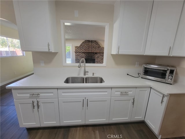 kitchen with dark hardwood / wood-style floors, a textured ceiling, white cabinetry, and sink