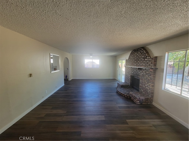 unfurnished living room with dark wood-type flooring, a textured ceiling, and a fireplace