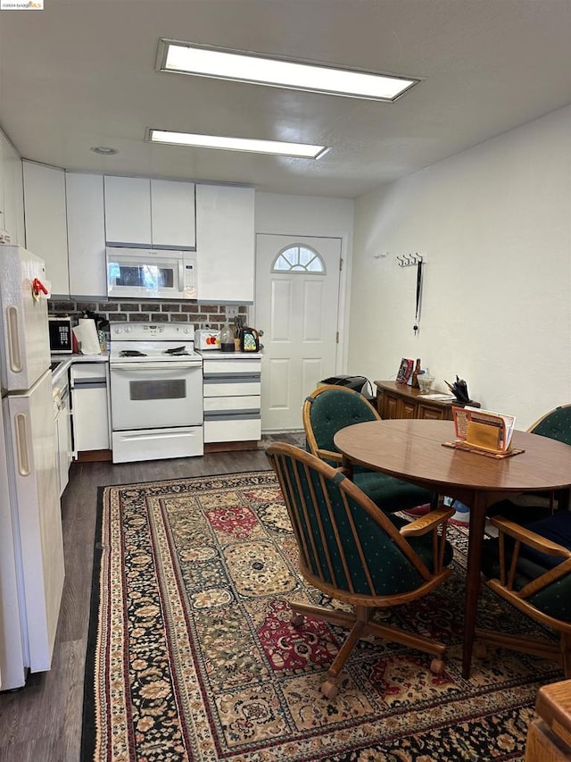 kitchen with white appliances, dark hardwood / wood-style floors, white cabinets, and tasteful backsplash