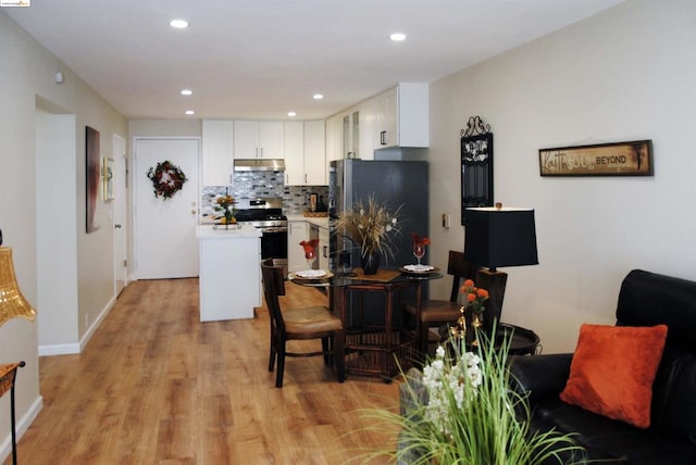 kitchen featuring decorative backsplash, stainless steel appliances, white cabinets, and light wood-type flooring