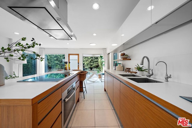 kitchen featuring oven, sink, white cabinetry, light tile patterned floors, and black electric cooktop