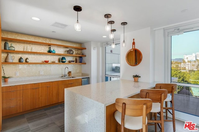 kitchen with decorative backsplash, light stone counters, a kitchen bar, decorative light fixtures, and sink