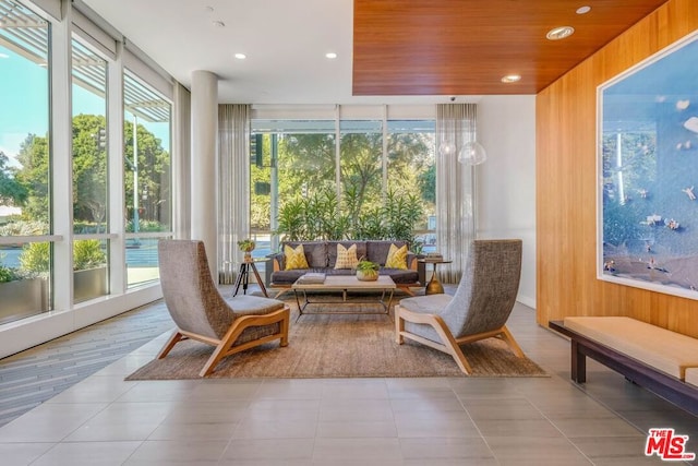 interior space with light tile patterned flooring, wood ceiling, wooden walls, and a healthy amount of sunlight