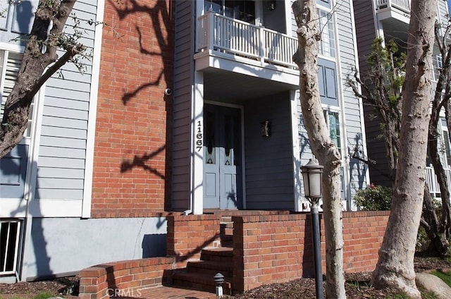 view of exterior entry with a balcony