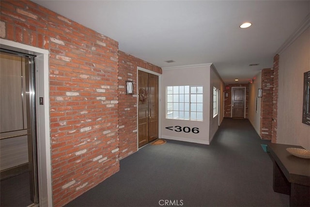 hallway featuring elevator, crown molding, and brick wall