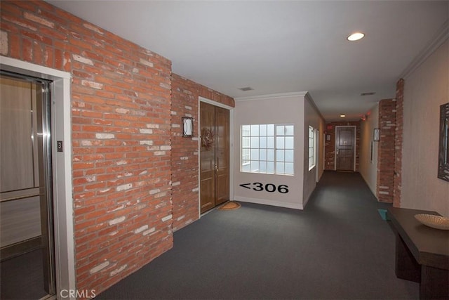 hallway with recessed lighting, ornamental molding, elevator, and brick wall