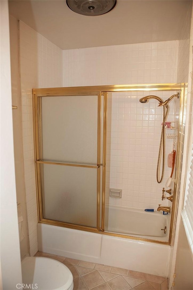 bathroom with tile patterned floors, bath / shower combo with glass door, and toilet