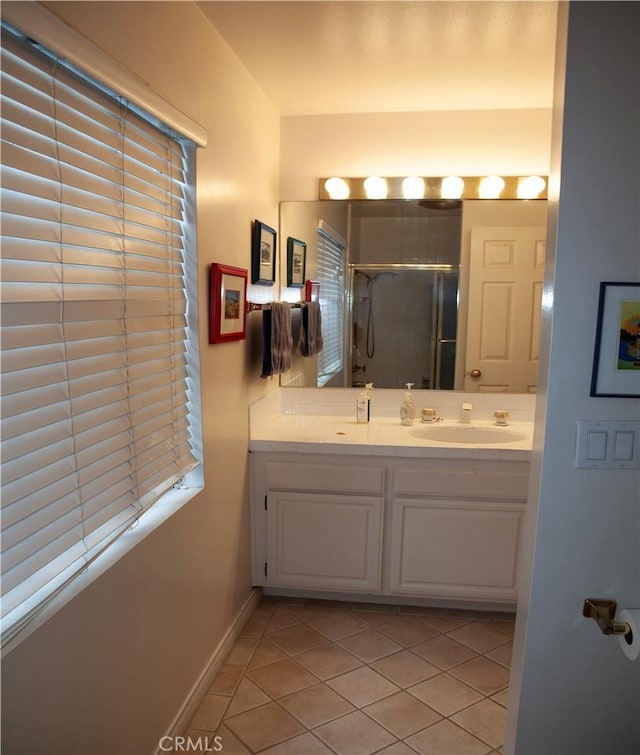 bathroom featuring double vanity, baseboards, tile patterned floors, a shower stall, and a sink