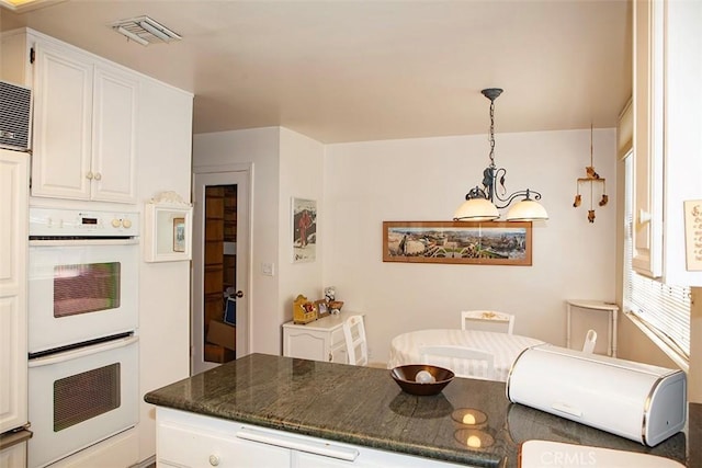 kitchen with white double oven, white cabinets, and hanging light fixtures