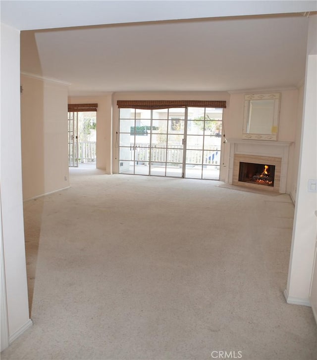 unfurnished living room with plenty of natural light, carpet, and a lit fireplace