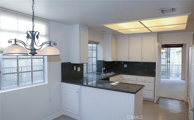 kitchen with dark countertops, a notable chandelier, a sink, decorative backsplash, and visible vents