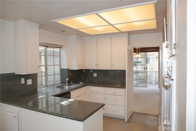 kitchen with a sink, backsplash, a peninsula, and white cabinetry