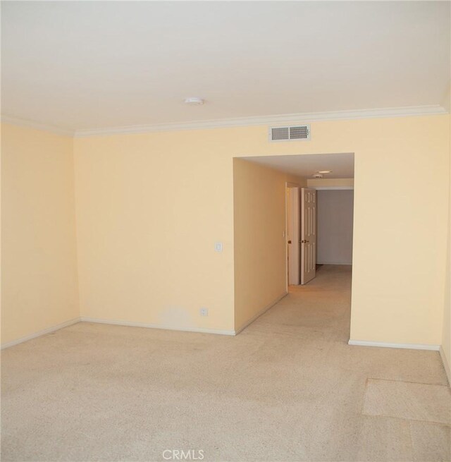 unfurnished room featuring light colored carpet, crown molding, visible vents, and baseboards