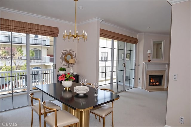 dining room featuring ornamental molding, carpet flooring, a warm lit fireplace, and a chandelier