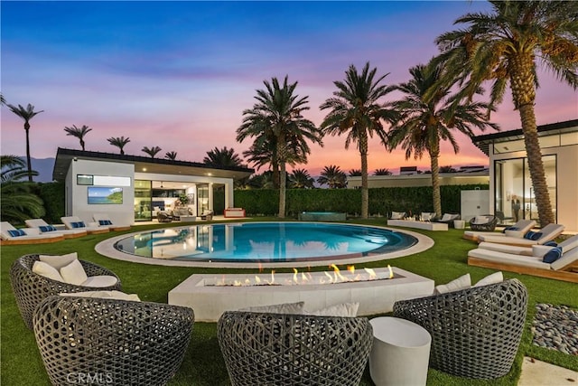 pool at dusk featuring a yard