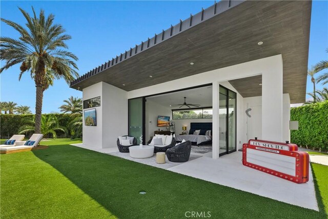 rear view of property with ceiling fan, a patio area, an outdoor hangout area, and a yard