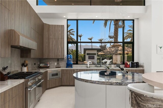 kitchen with appliances with stainless steel finishes, tasteful backsplash, a healthy amount of sunlight, and wall chimney range hood