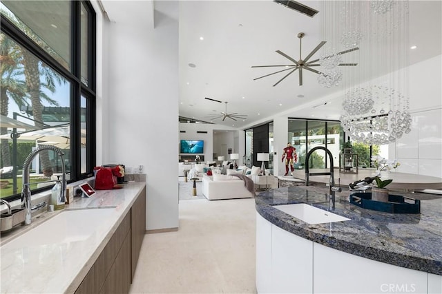 interior space featuring plenty of natural light, white cabinets, dark stone counters, and sink