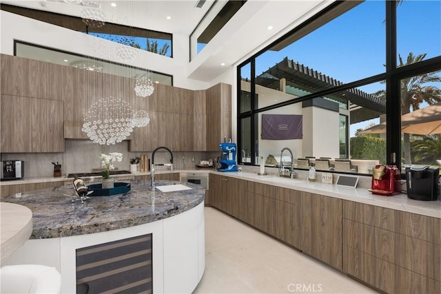 kitchen with backsplash, wine cooler, sink, and an inviting chandelier