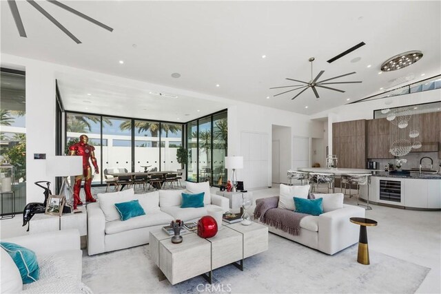 living room with ceiling fan, sink, and a wall of windows