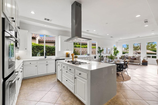 kitchen featuring light tile patterned flooring, island range hood, white cabinetry, a center island, and stainless steel appliances