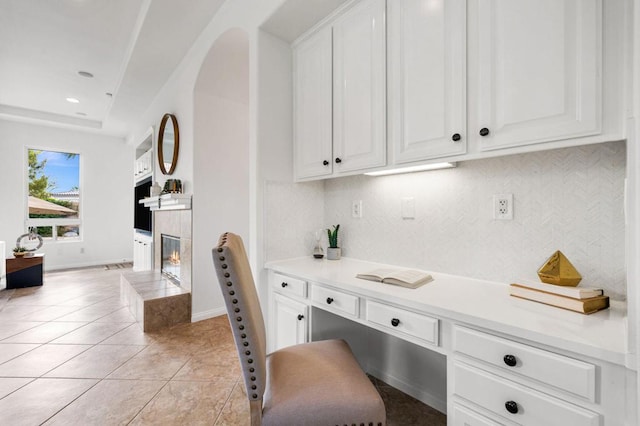 interior space featuring white cabinetry, light tile patterned floors, and a tile fireplace