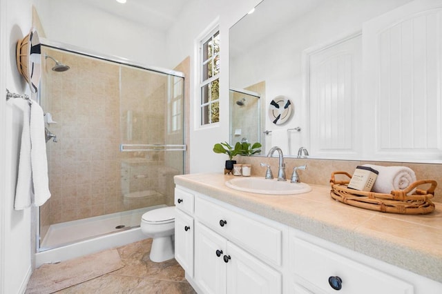 bathroom featuring a shower with door, vanity, tile patterned floors, and toilet