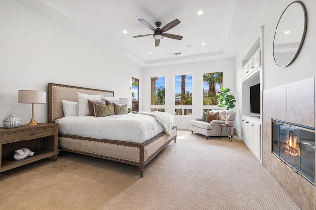 carpeted bedroom with a raised ceiling, ceiling fan, and a fireplace