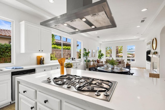 kitchen with stainless steel gas cooktop, island range hood, dishwasher, a wealth of natural light, and white cabinets