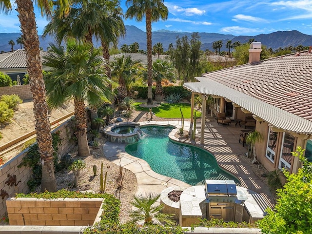 view of pool featuring an in ground hot tub, an outdoor kitchen, a mountain view, and a patio