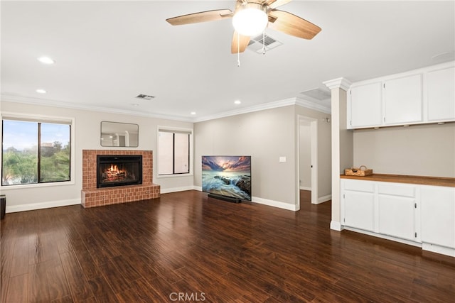 unfurnished living room with dark hardwood / wood-style floors, a fireplace, crown molding, and ceiling fan