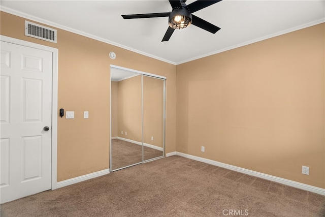 unfurnished bedroom with a closet, ceiling fan, crown molding, and carpet