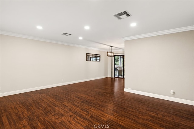 spare room featuring ornamental molding, dark wood-type flooring, and a chandelier