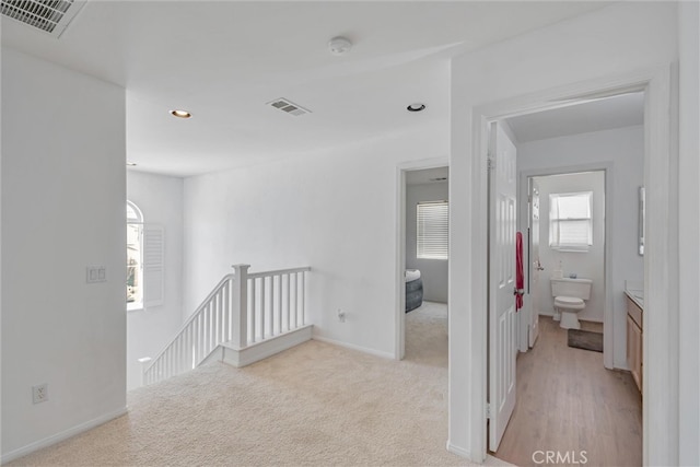 corridor featuring light colored carpet and plenty of natural light